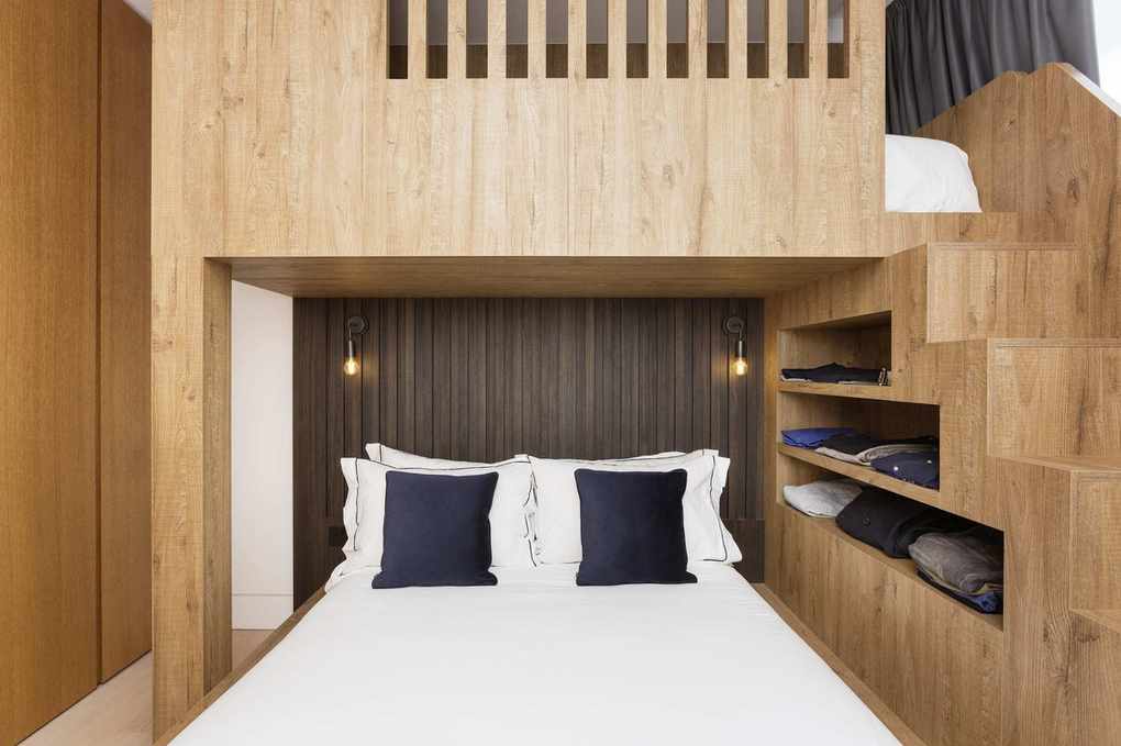 small modern bedroom with custom built shelving for clothes, bed with white bedding, wall lights
