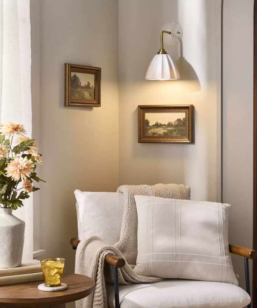 Living room nook with cream armchair, overhead lighting, and flower vase