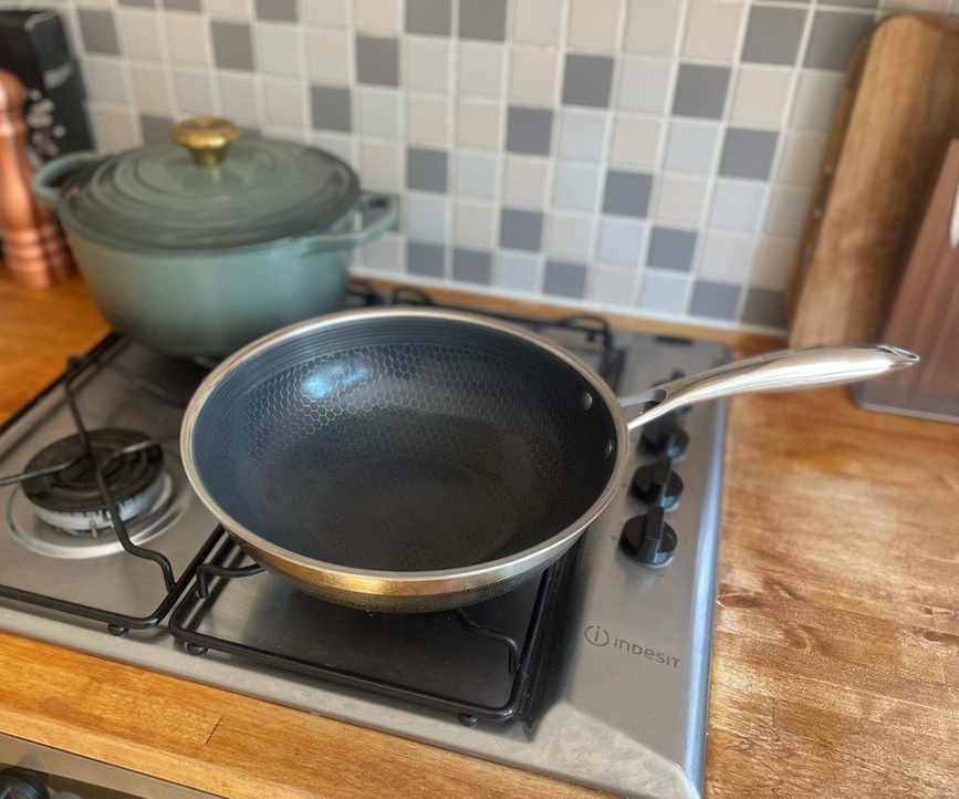 A large HexClad wok on a gas stove set into a wooden counter