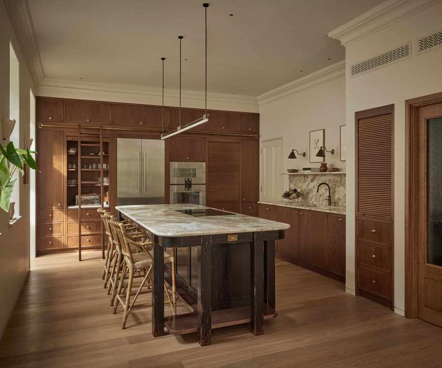 A large kitchen with mid-toned wood cabinets and a dark wood kitchen island