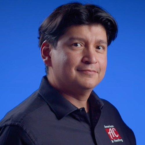 Headshot of Omero Flores in a blue polo shirt with company logo against a blue background.