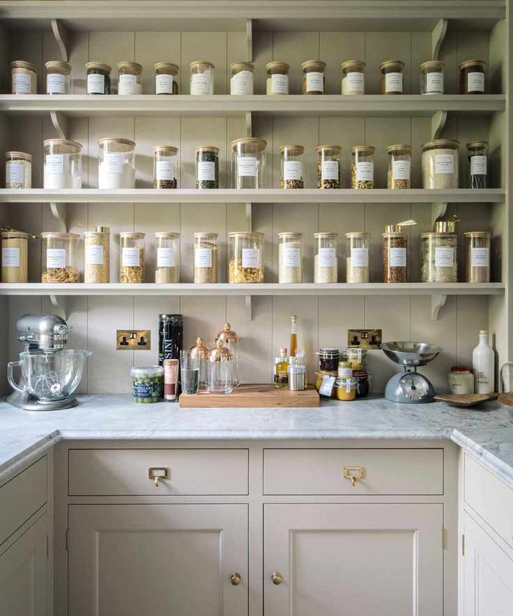 A neutral walk in pantry with matching glass jars on open shelving