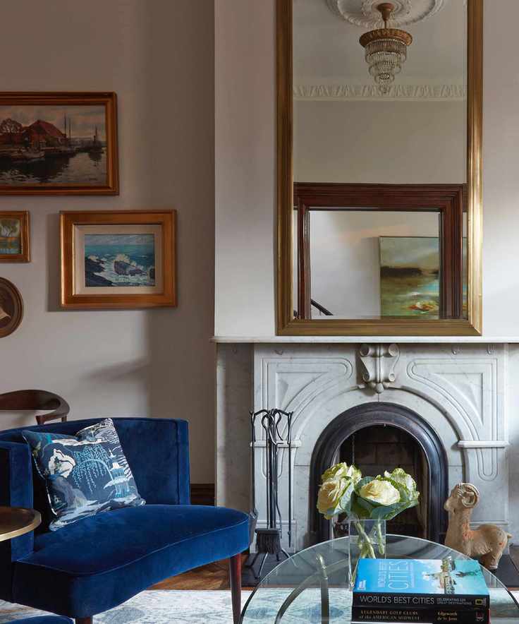 timeless interior design styles, living room with vintage/bohemian style, blue armchair, large mirror, chandelier, gold framed art