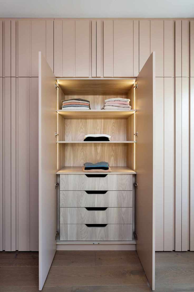 closet doors in pale pink with a section open to reveal drawers and shelving, LED lighting, wooden floor