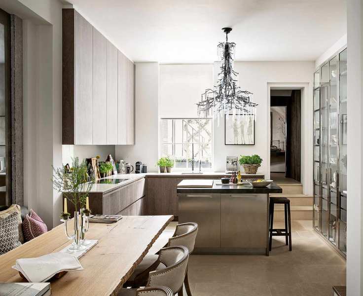 Grand chandelier over a chrome breakfast bar, with wooden cabinetry and a large dining table