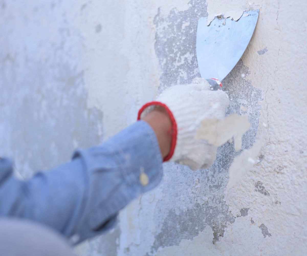 Someone removing paint from wall