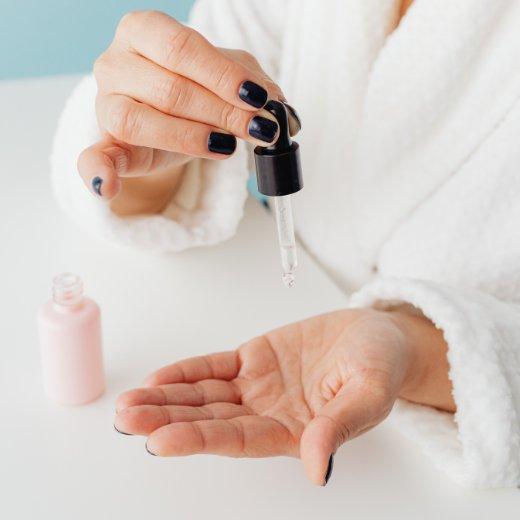 Woman applying skincare serum into hand for application