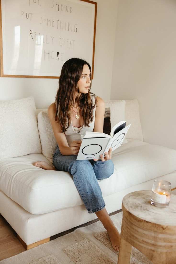 woman reading book on couch