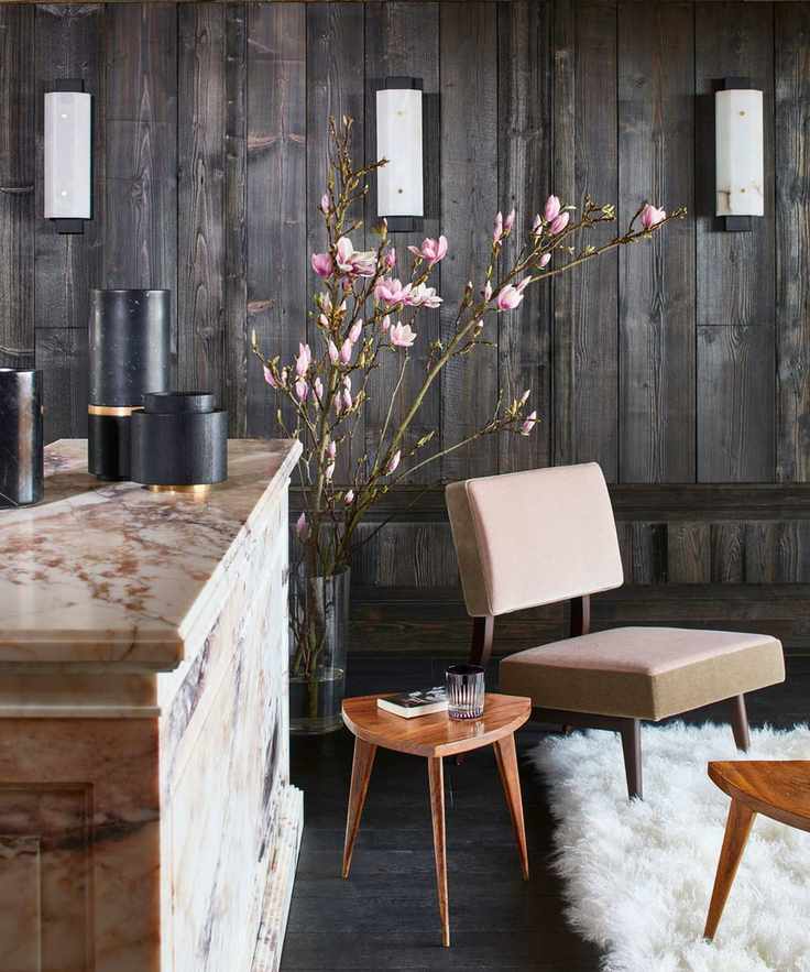 A dark wood walled room with a leather chair and dried grass
