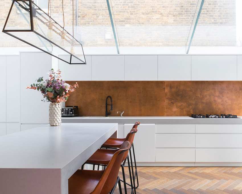A kitchen showcasing a side return extension with parquet flooring and a striking ceiling lamp