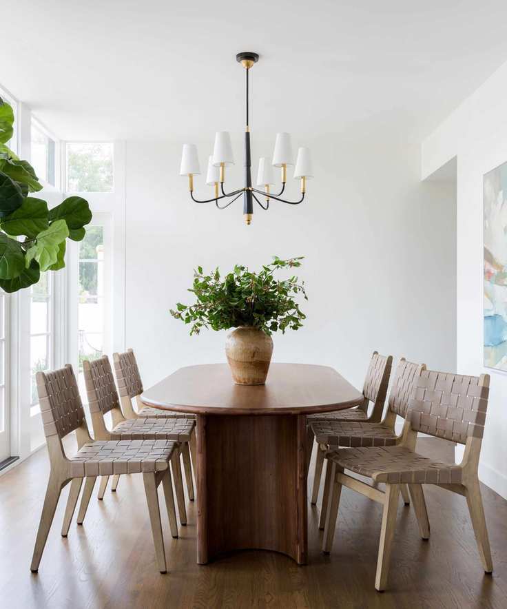 Dining room with white walls woven chairs and oval wooden table