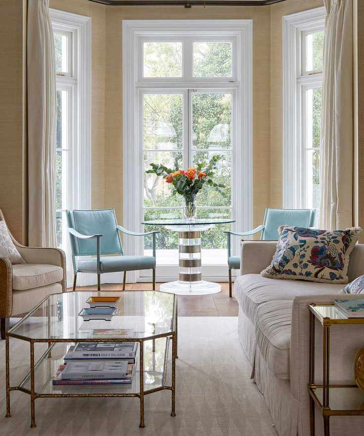 Beige living room with textured wallpaper, vibrant blue chairs, and large windows.