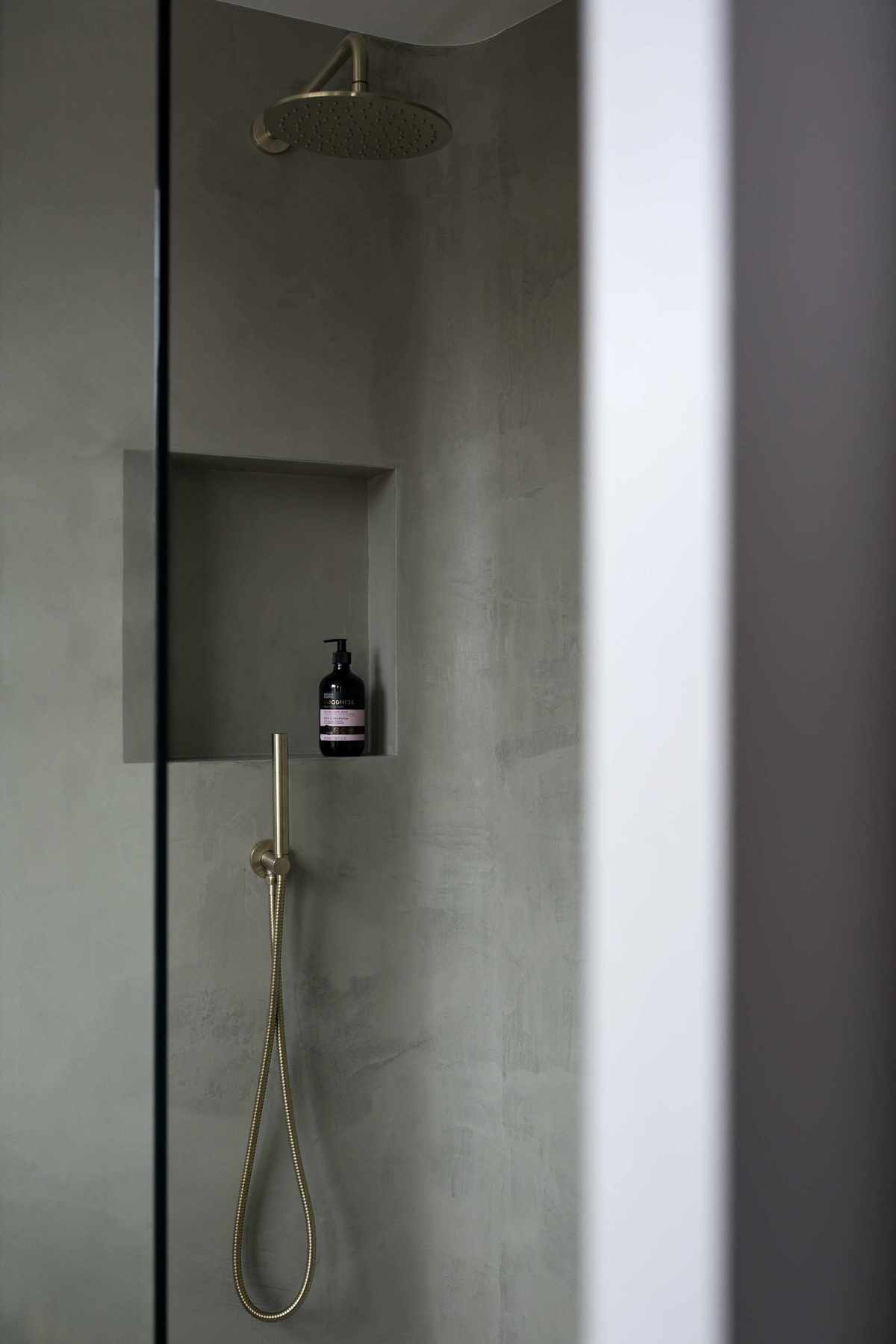 walk in shower with mid grey walls, alcove shelf, brass shower head