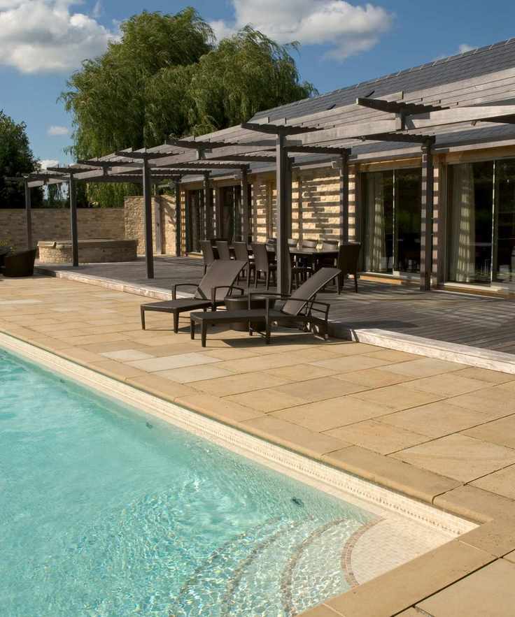 Expansive pool house with timber structure and patio area for dining and lounging.