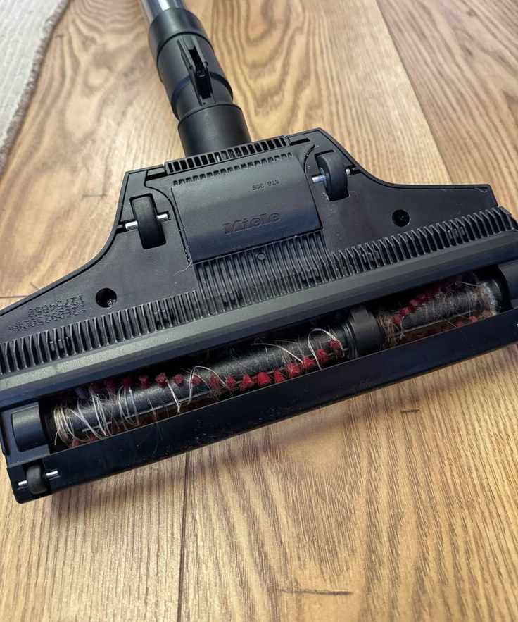 Miele Guard L1 Cat and Dog floorhead on wooden floor with hair caught in brushroll.