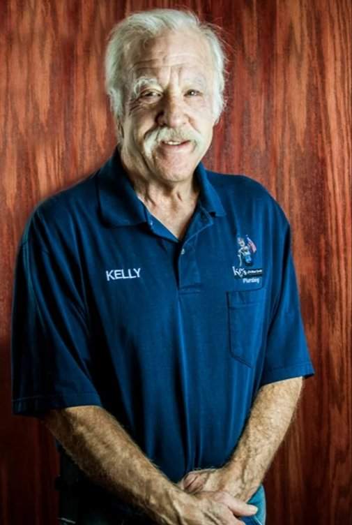 Kelly Russum in blue polo in front of brown wooden background.