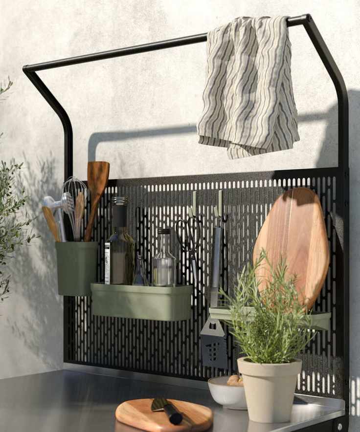 Outdoor kitchen with steel work surface, kitchen utensils, wood chopping board and rosemary potted plant