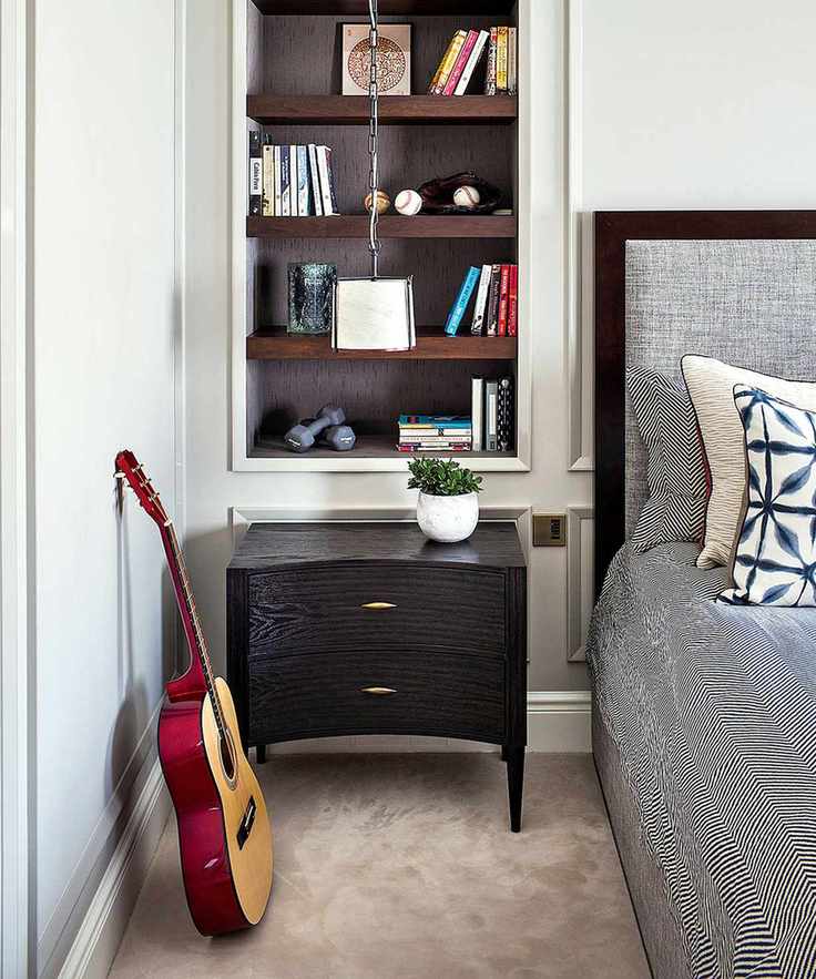 Bedroom featuring a grey headboard, bedding, and alcove shelves filled with books and ornaments.
