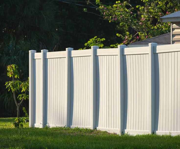 A white vinyl fence in a backyard