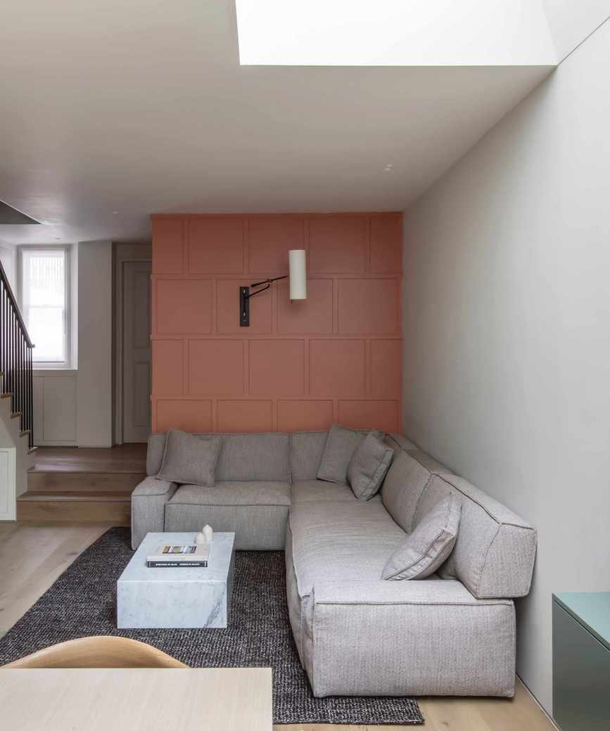 accent walls, coral panelled accent wall with wall light, grey sectional, textured rug, marble coffee table