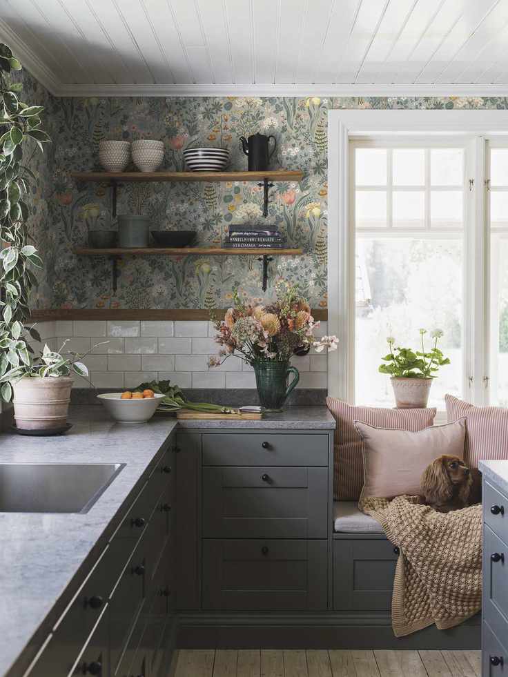light green wallpaper in Scandi style kitchen featuring dark gray cabinets a window seat and a dog