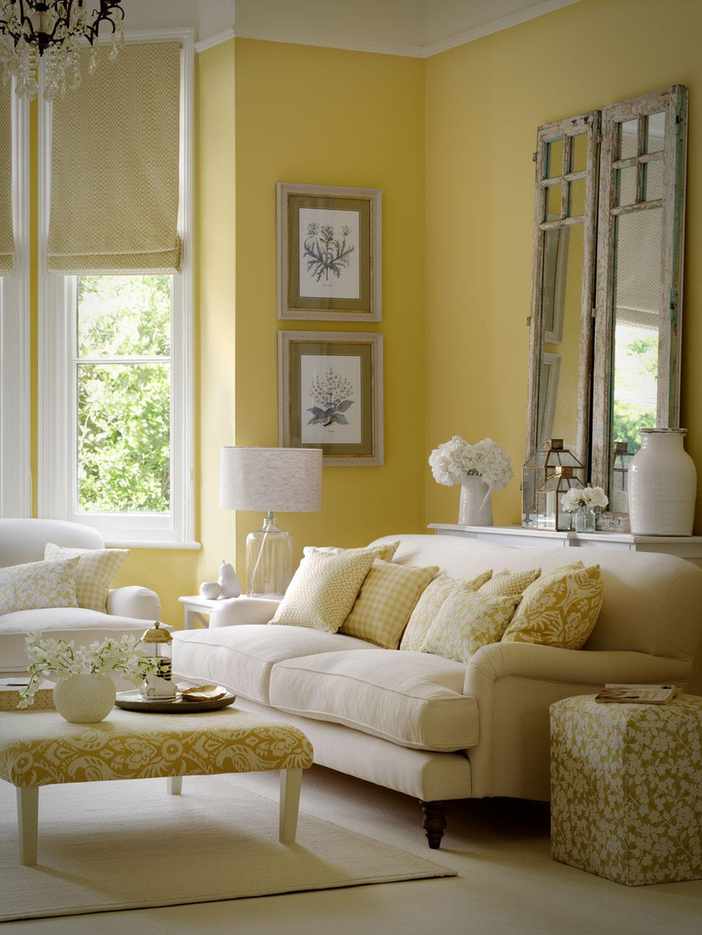 A yellow living room with an off-white sofa and patterned footstool