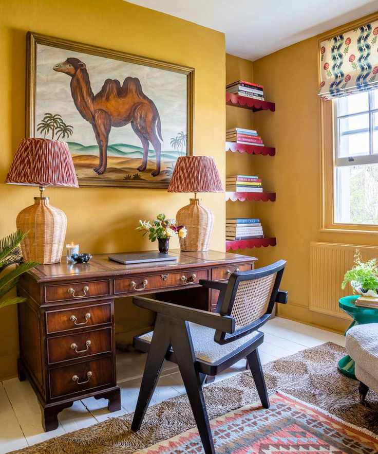 Sean Symington yellow study with antique dark wood desk, camel painting and layered rugs