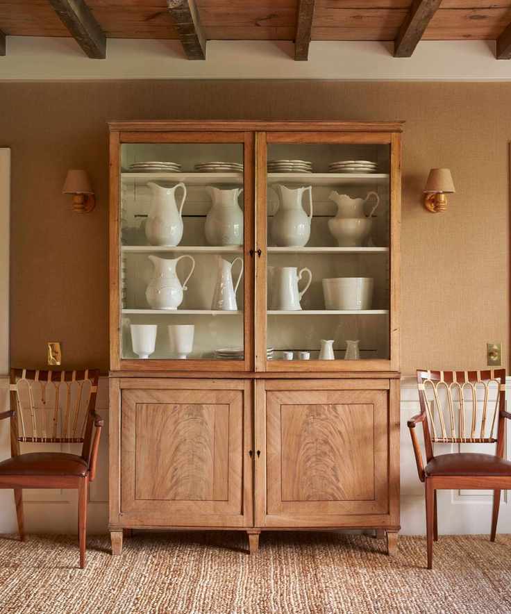 Wood dresser with white ceramic jugs and tableware and two wooden antique chairs