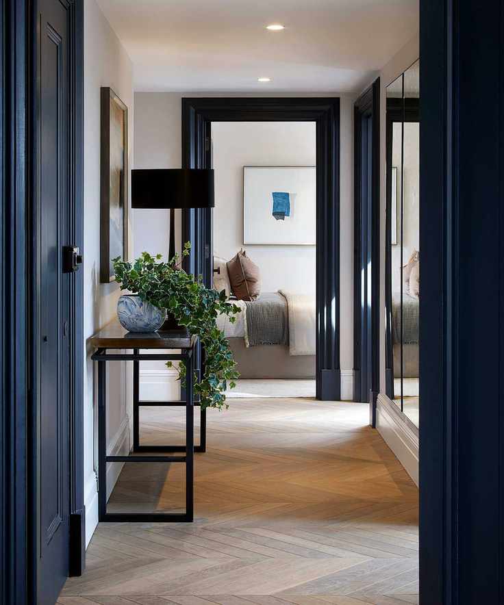 Small hallway with dark blue paint, console table, and herringbone flooring.