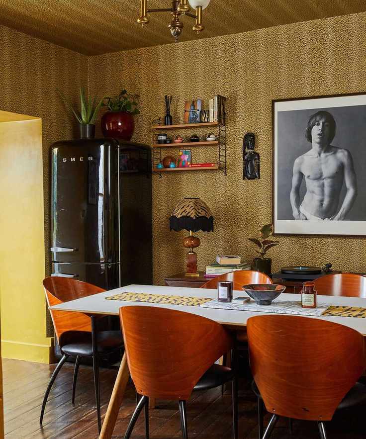 Leopard print wallpaper with dining table and wood midcentury chairs and framed photograph