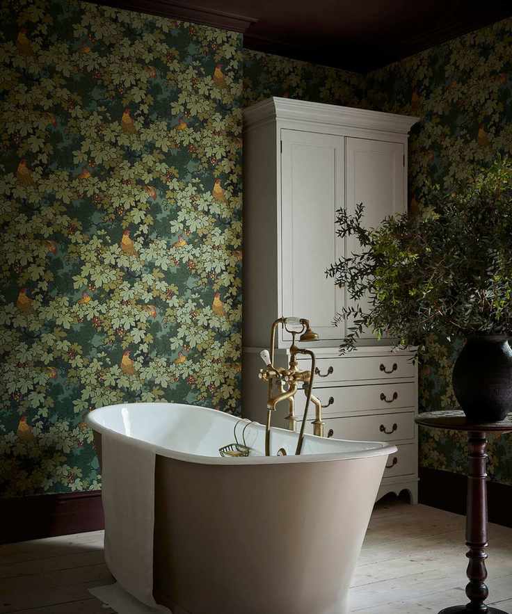 Little greene wallpaper in a bathroom in dark green with a freestanding white bathtub
