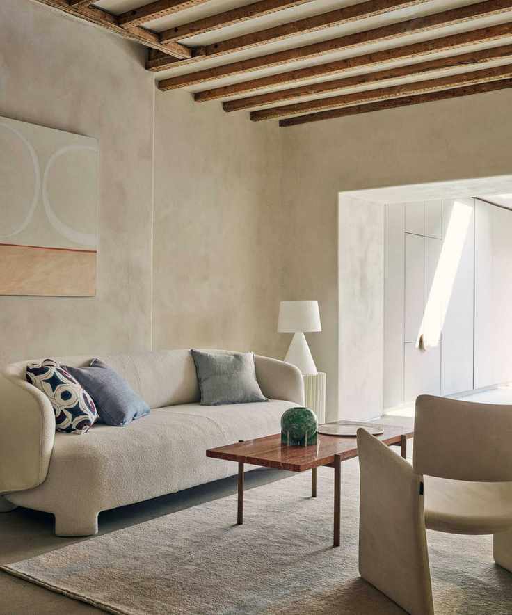 Living room with curved white sofa, abstract art work and red marble top coffee table