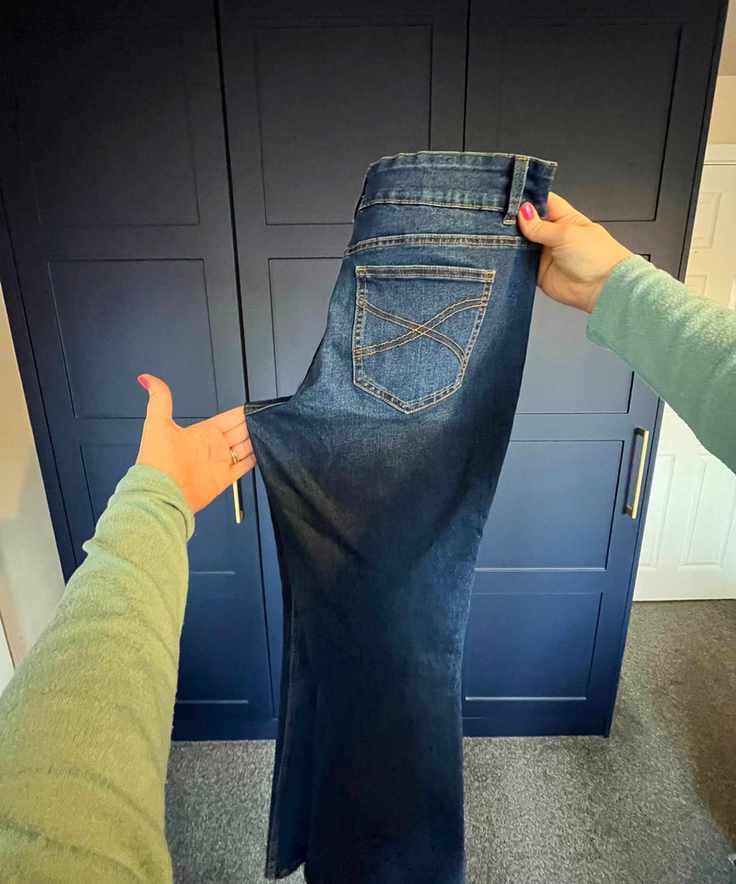 Pictured is the pair of jeans now folded vertically so the zip falls inside and you can now see the in-seam on the left side that is being pulled out to a point and neatened up