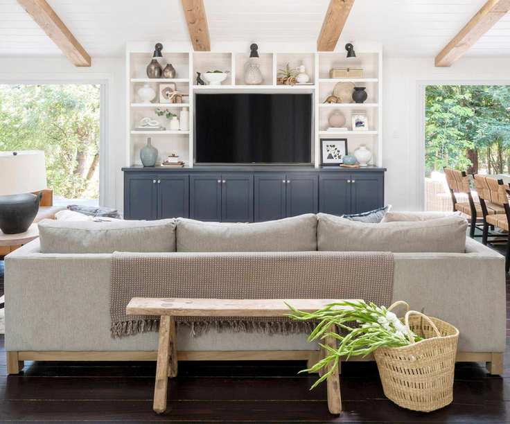 White living room with gray sofa and wall mounted tv with storage built around
