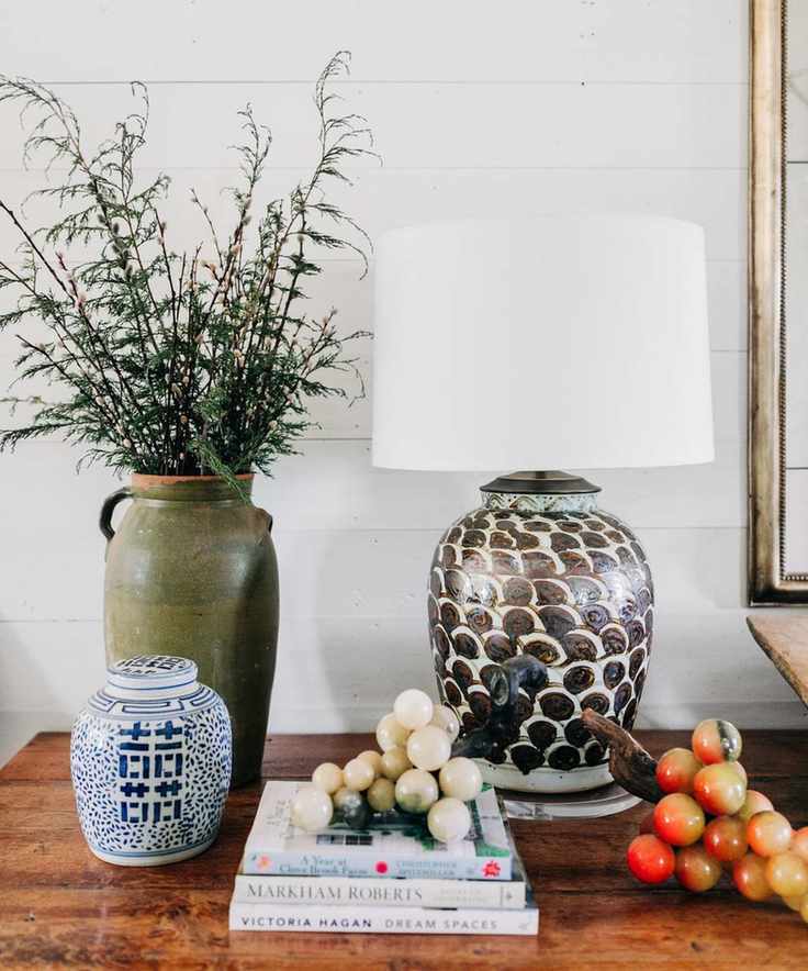 A console table with a lamp, vase and a stack of books