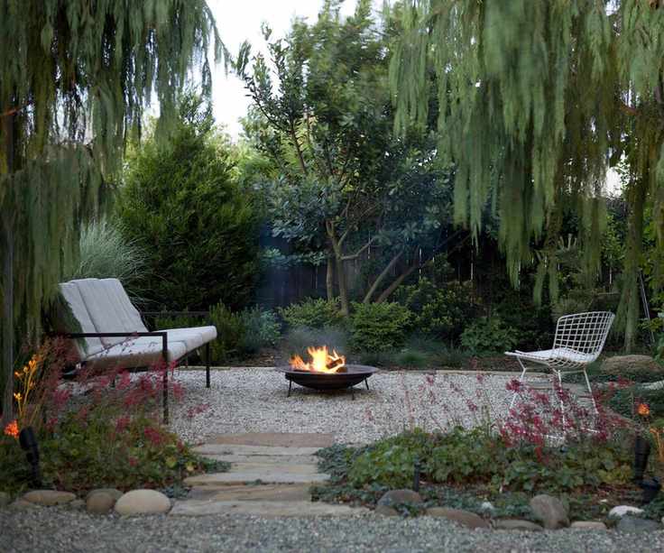 gravel patio area under trees with seating and fire pit