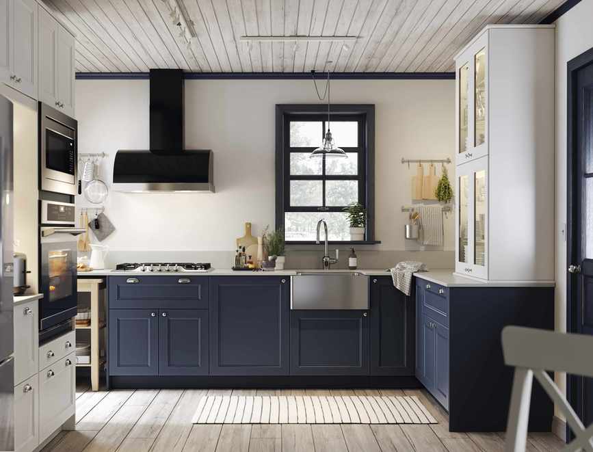 Blue kitchen ideas with navy blue painted cabinetry in a white kitchen with wooden flooring and steel sink.