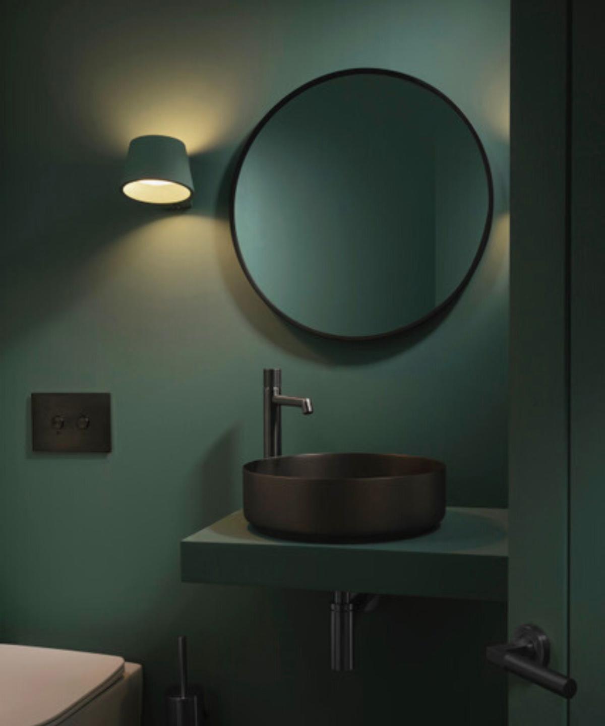 Dark green bathroom with a black rimmed mirror and wall light