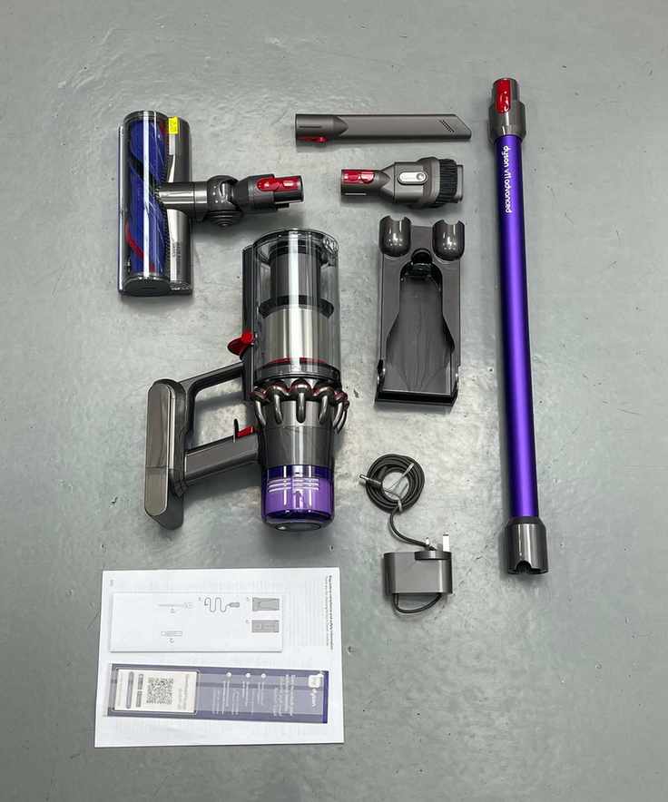 All parts and attachments of the Dyson V11 laid out on linoleum floor in Future test center.