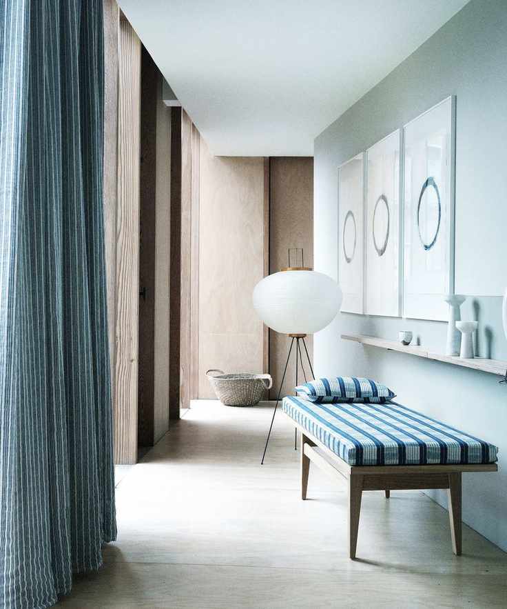 Hallway showcasing a bench with blue cushions, a floor lamp, and artwork