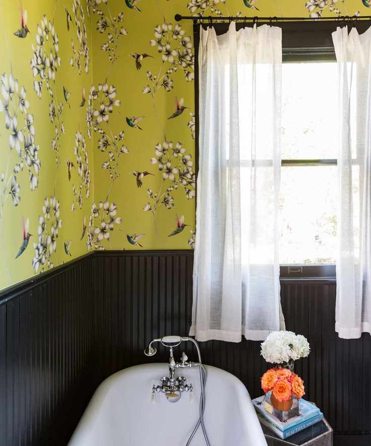 A bathroom adorned with yellow floral wallpaper and elegant black paneling.
