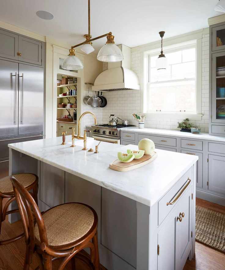 A white and grey kitchen adorned with vintage gold hardware