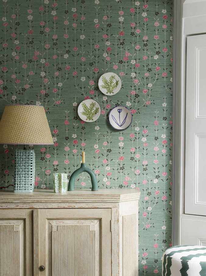 pink and green wallpaper behind console with plates on wall and lamp