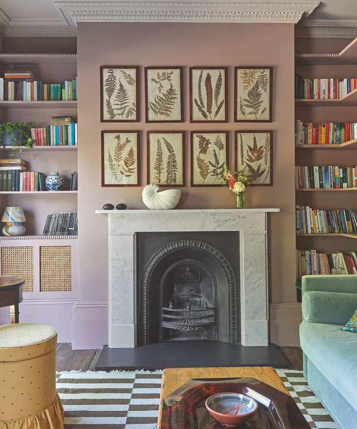 Maximal living room with botanical prints above fireplace and striped rug and bookshelves