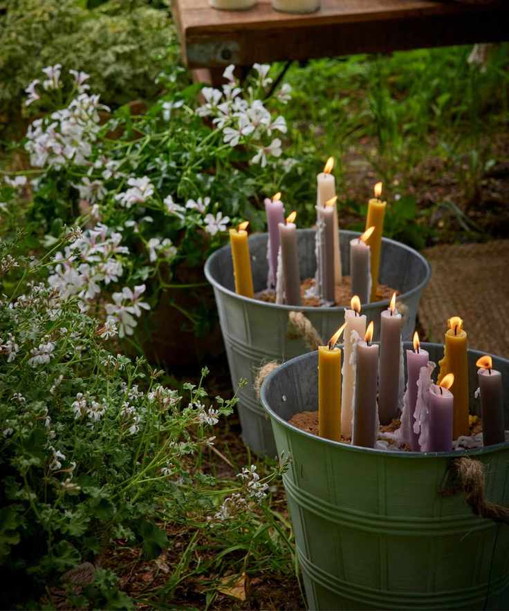 garden greenery with buckets filled with sand and candles