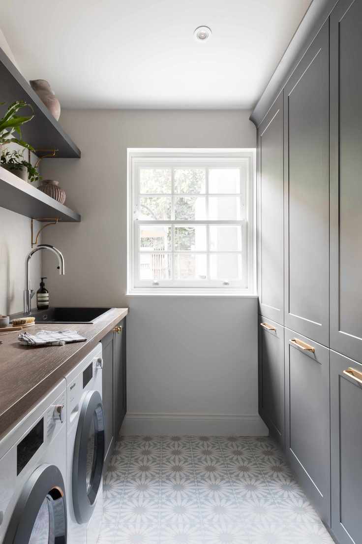 Narrow utility room showcasing grey cabinetry and patterned tile flooring