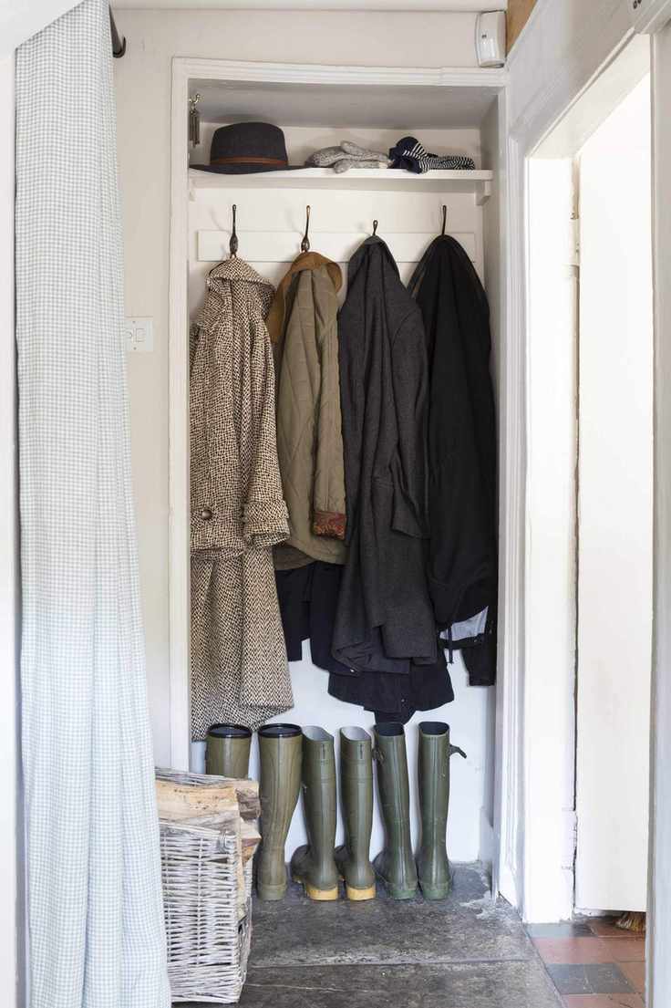 A small walk-in closet converted into a mudroom with wellies and coats