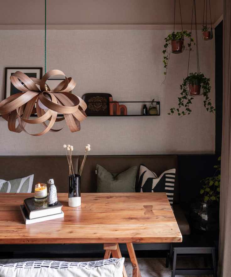 warm vs cool colors, neutral dining space with hanging plants, bent wood pendant light, bench seating, earthy colors, open shelf