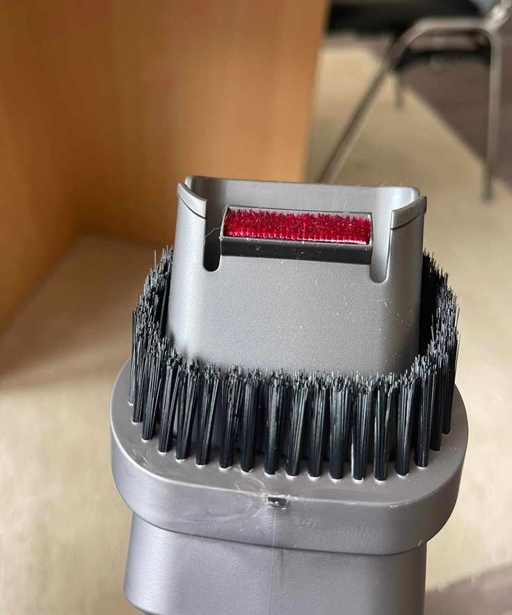 Closeup of the Dyson V11's combination tool vacuum attachment in Bristol ARC, pictured in front of cream rug and wooden table legs.