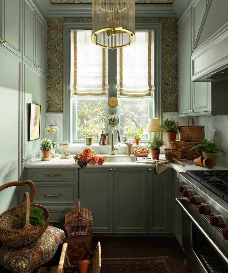 a soft green pantry with floral wallpaper on the ceiling, a window dressed with linen blinds and lots of potted plants and flowers decorating the countertop and window